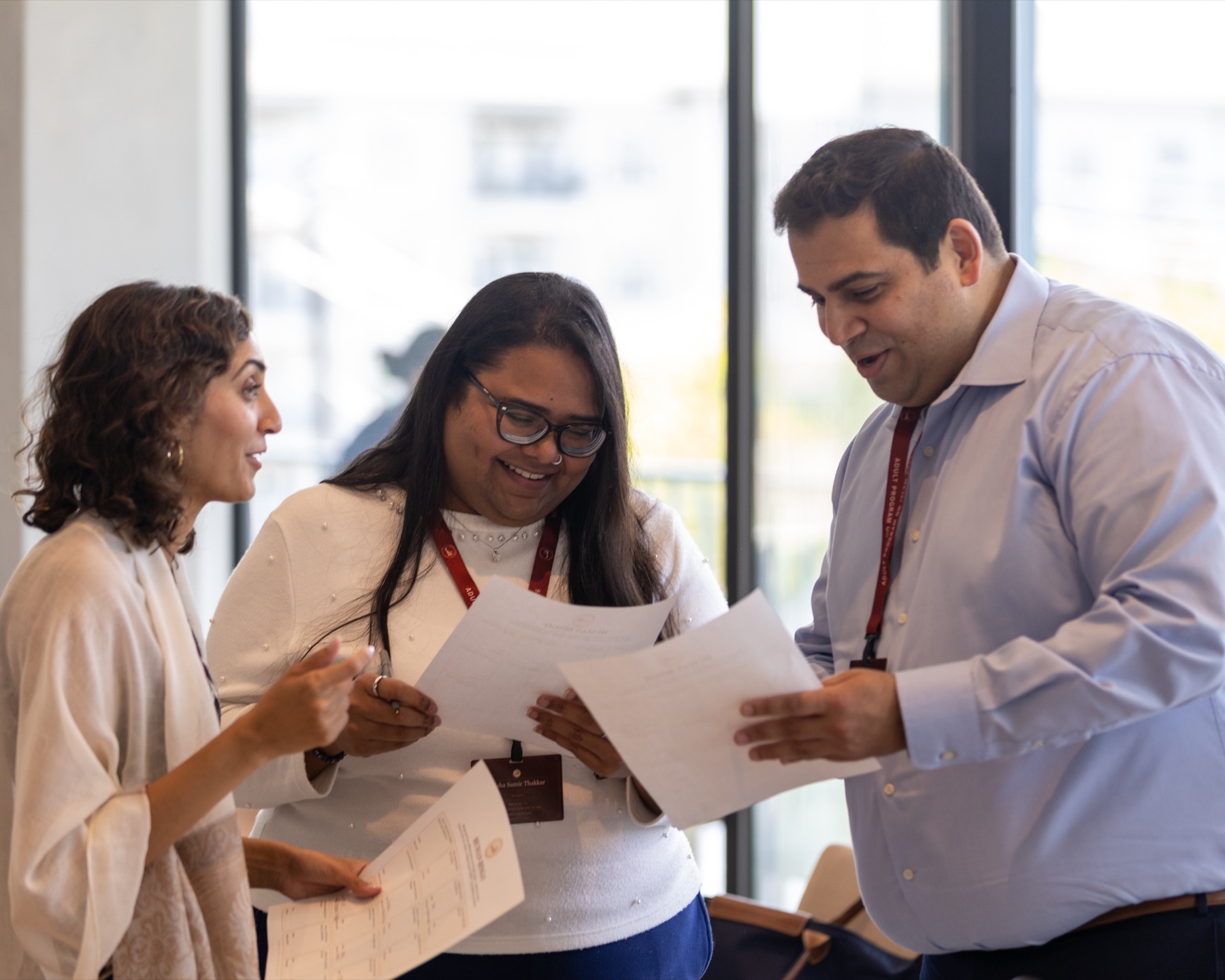 Three participants talking and comparing handouts during an opening activity.